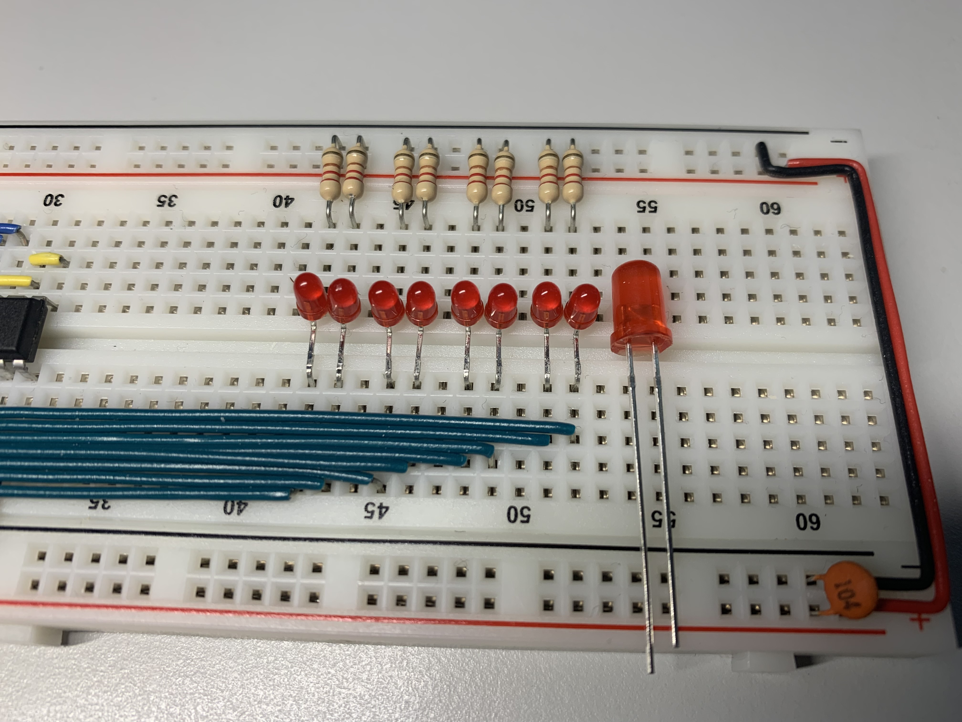 An image of a populated breadboard with the 3mm LEDs next to each other and a 5mm LED laid next to them to show the size difference.